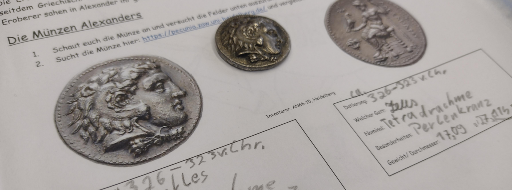 Nahaufnahme eines Dokuments über die Münzen Alexanders des Großen, das Abbildungen und Beschreibungen antiker Münzen mit dem Profil Alexanders und griechischem Text sowie handschriftliche Notizen in deutscher Sprache zeigt. Nahaufnahme eines Dokuments über die Münzen Alexanders des Großen, das Abbildungen und Beschreibungen antiker Münzen mit dem Profil Alexanders und griechischem Text sowie handschriftliche Notizen in deutscher Sprache zeigt.