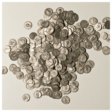 Auf einer hellen Fläche ist ein großer Haufen verstreuter Münzen ausgebreitet, wobei sich einige Münzen überlappen und andere voneinander entfernt sind.